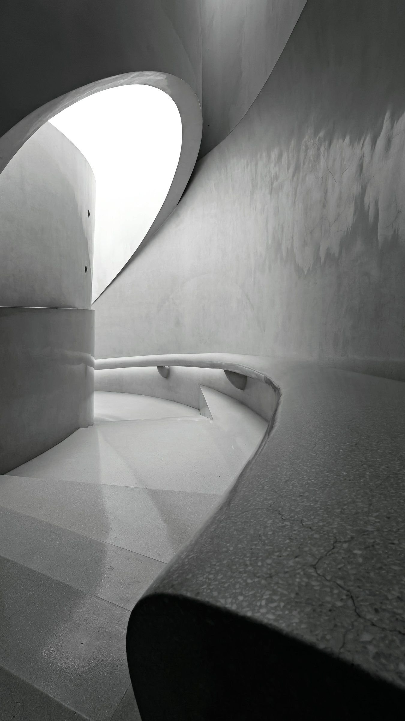 Sweeping concrete curves and an arched opening in black and white