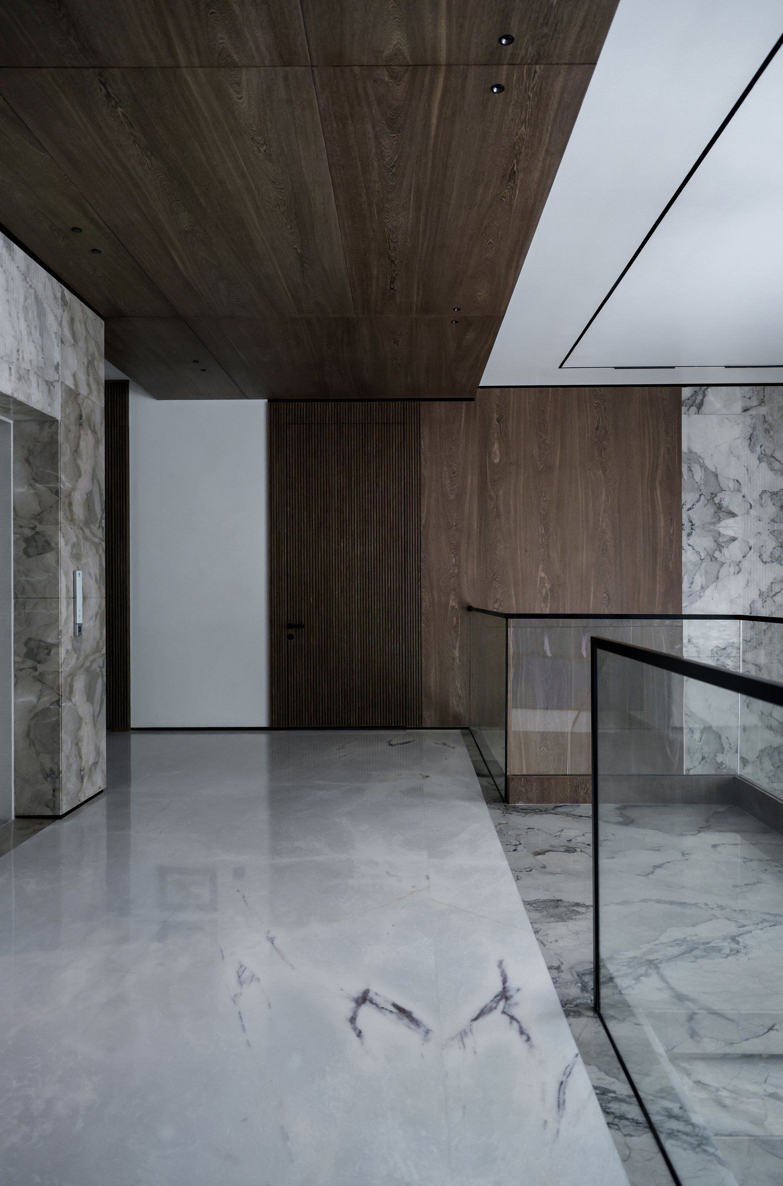 A calm interior with a timber ceiling, marble floor and glass balustrade