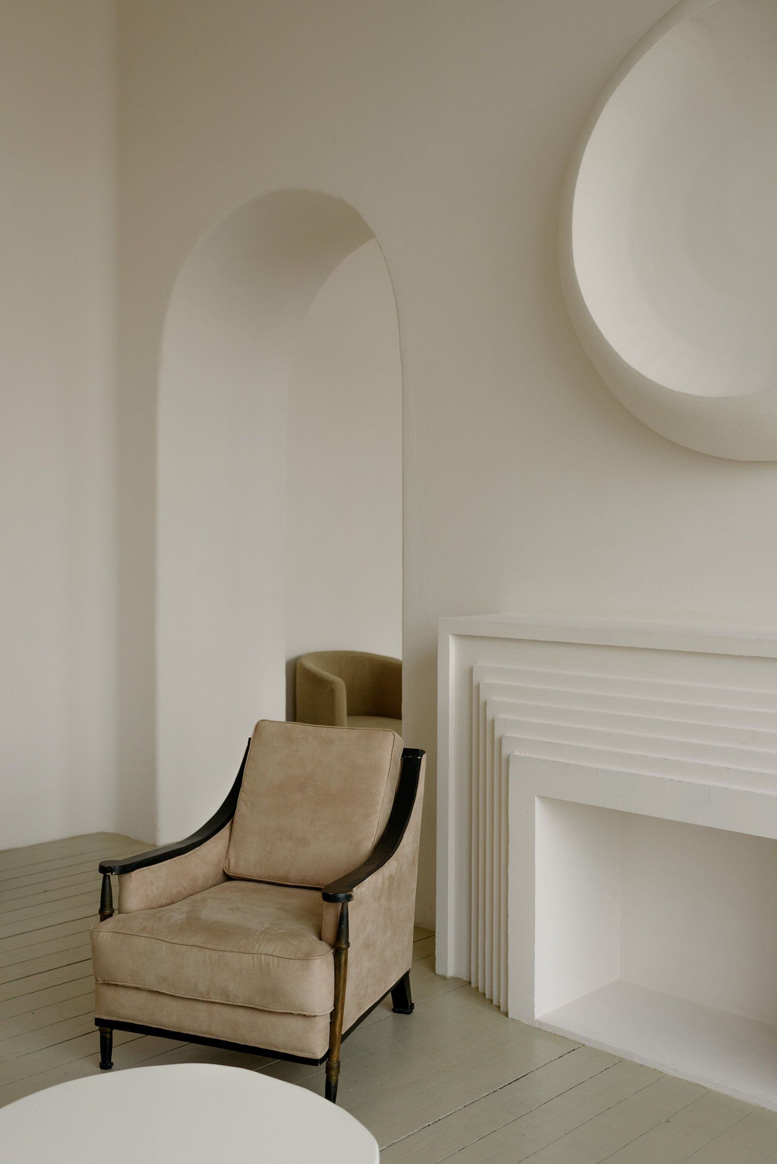 A soft interior with an arched niche and a single armchair